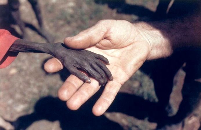دستان کودک نحیف اوگاندایی در دستان کشیش کاتولیک